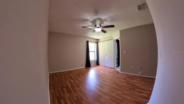 a view of an empty room with window and wooden floor