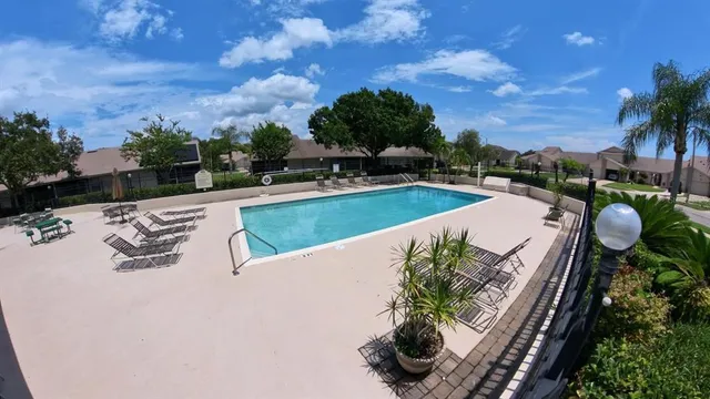 a view of a swimming pool and lounge chairs in back yard of a house