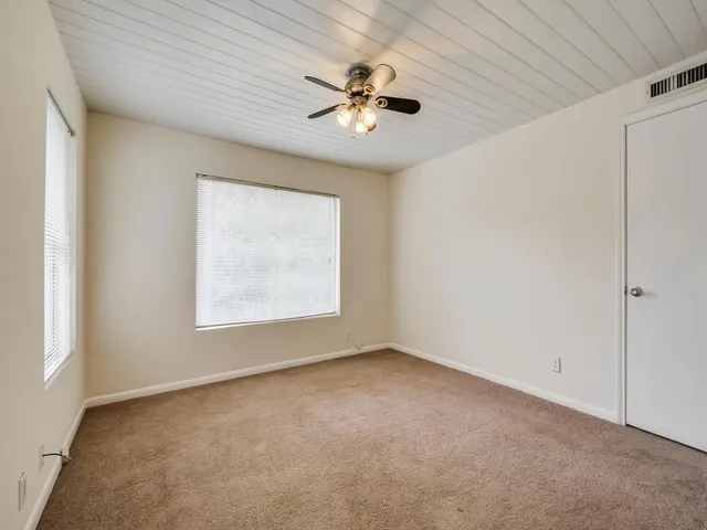 an empty room with a window and a ceiling fan
