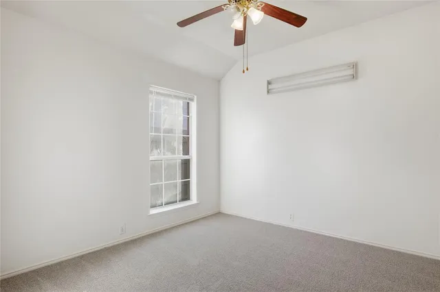 an empty room with a window and a ceiling fan