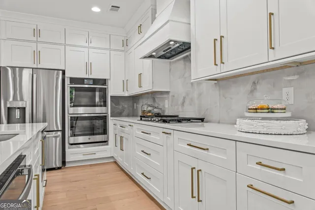 a kitchen with stainless steel appliances granite countertop a refrigerator and white cabinets
