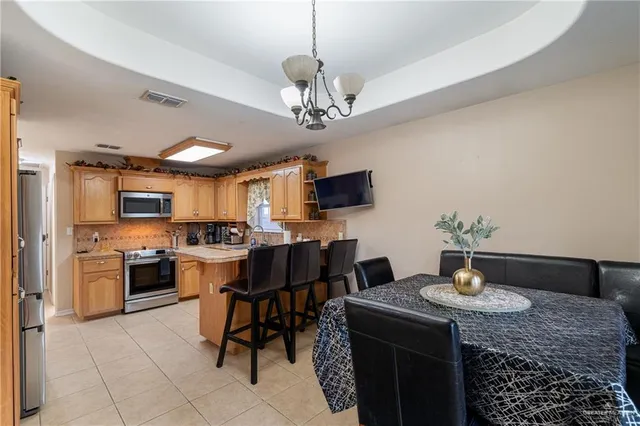a kitchen with stainless steel appliances granite countertop a sink dishwasher a stove a refrigerator a microwave oven with a dining table and chairs