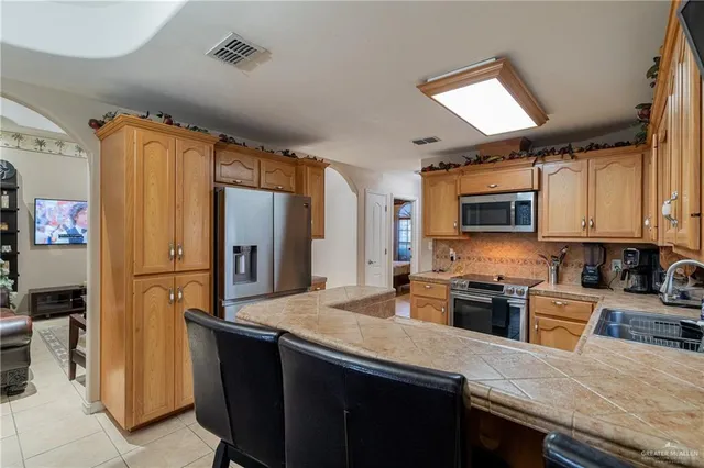 a kitchen with stainless steel appliances granite countertop a refrigerator a stove top oven a sink and dishwasher
