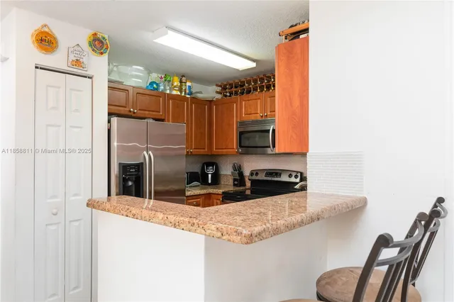 a kitchen with stainless steel appliances granite countertop a sink and a refrigerator