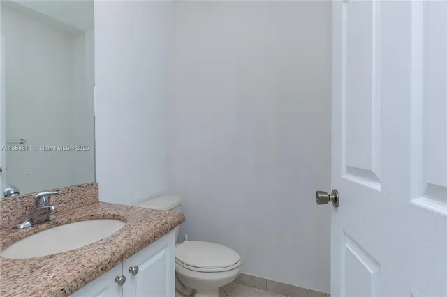 a bathroom with a granite countertop sink toilet and a mirror