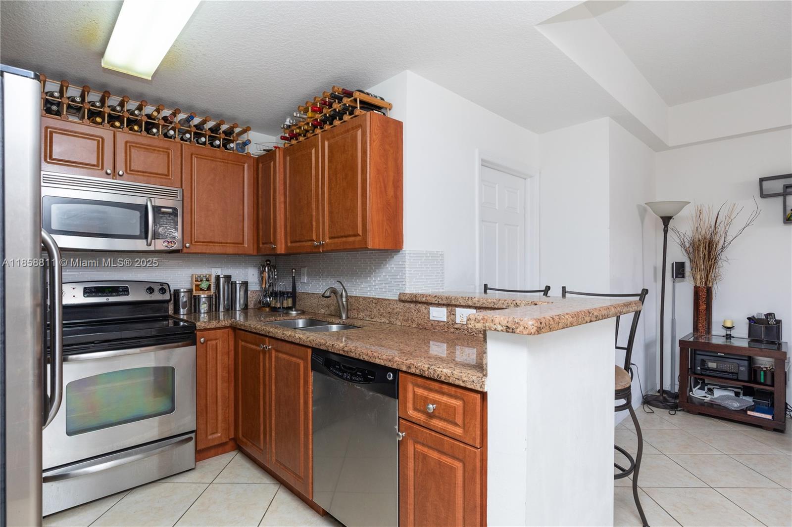 1068 Southwest 143rd Avenue, Unit 2510 Pembroke Pines, FL 33027 - Photo 9 of 49 a kitchen with kitchen island granite countertop a sink stove and cabinets