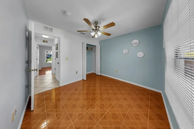 an empty room with windows and fan