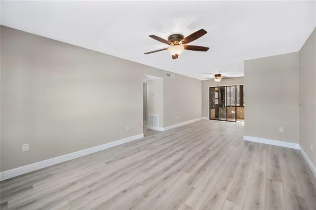 a view of empty room with wooden floor and ceiling fan