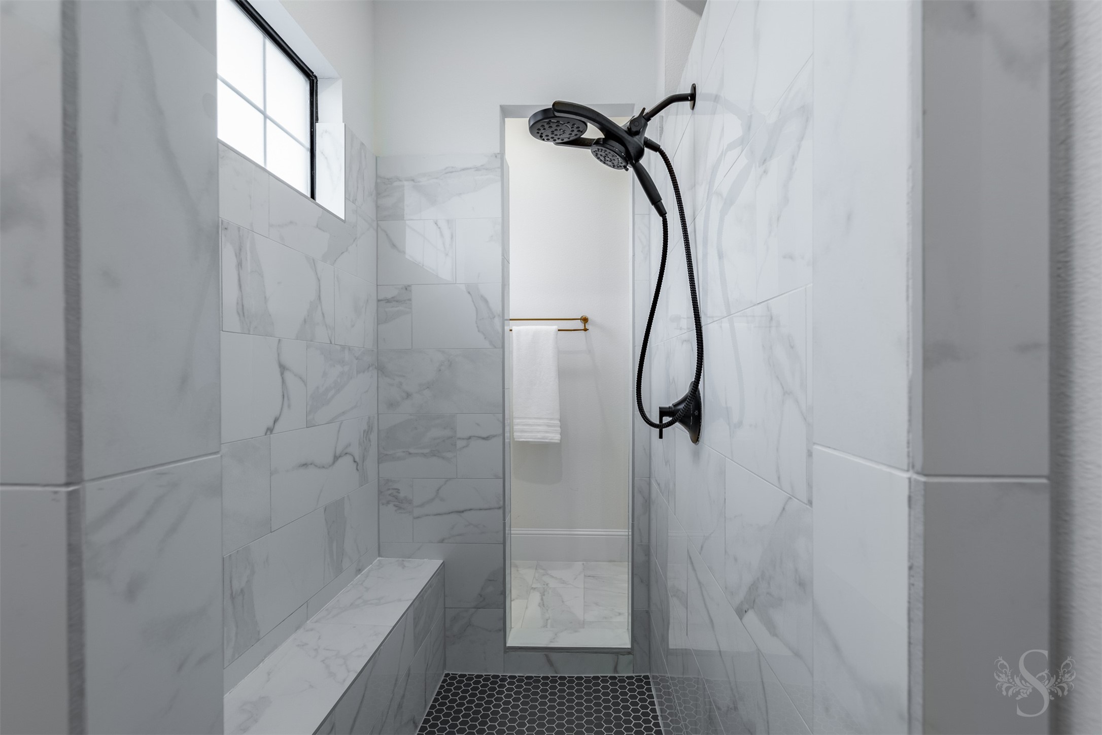 27919 Indigo Ridge Drive Fulshear, TX 77441 - Photo 29 of 50 This sleek walk-through shower offers a spa-level experience with marble-look tile, dual shower heads, and a built-in bench. Natural light filters through the privacy window, enhancing the serene atmosphere of this beautifully designed retreat.
