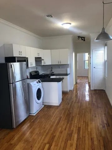 a kitchen with stainless steel appliances granite countertop a refrigerator a stove top oven a sink and dishwasher with wooden floor