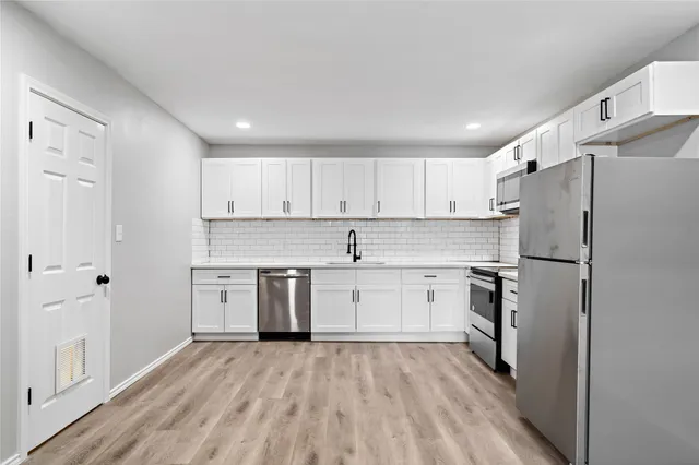 a kitchen with a refrigerator a sink and dishwasher with wooden floor