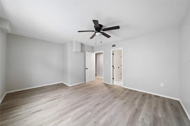 a view of empty room with wooden floor and ceiling fan