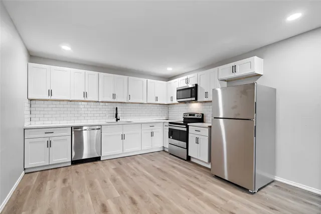 a kitchen with a refrigerator stove top oven and white cabinets