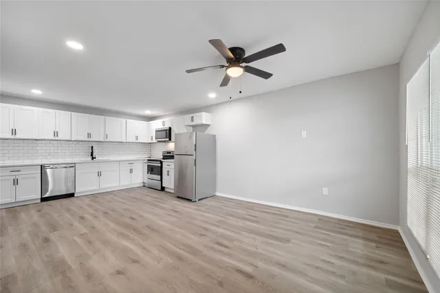 a view of a kitchen with a sink and dishwasher a refrigerator with wooden floor