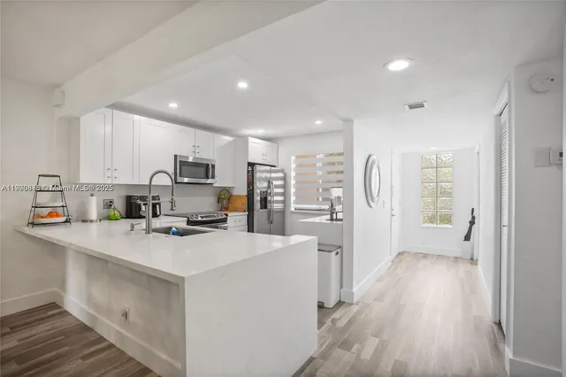 a kitchen that has a lot of cabinets a sink and wooden floor