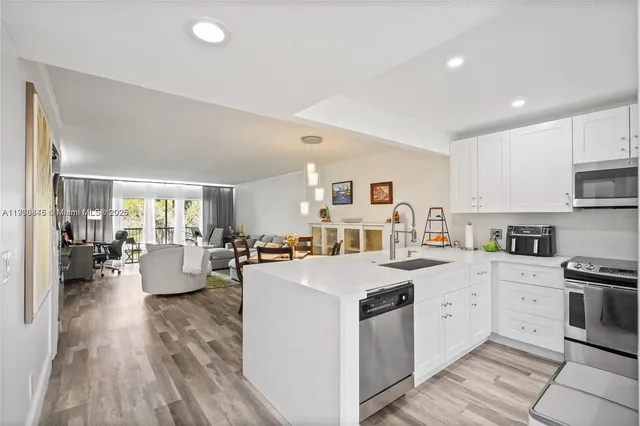 a large white kitchen with cabinets a sink a stove a dining table and chairs