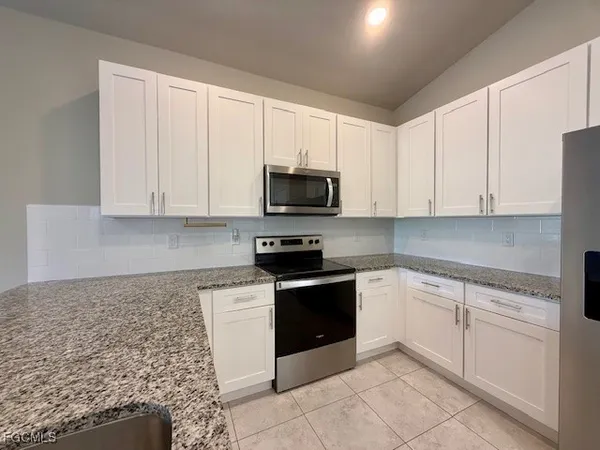 a kitchen with granite countertop white cabinets and stainless steel appliances