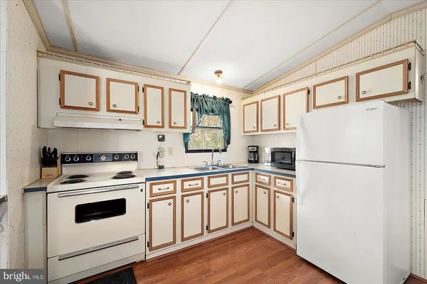 a white kitchen with stainless steel appliances granite countertop a refrigerator a stove a sink and white cabinets