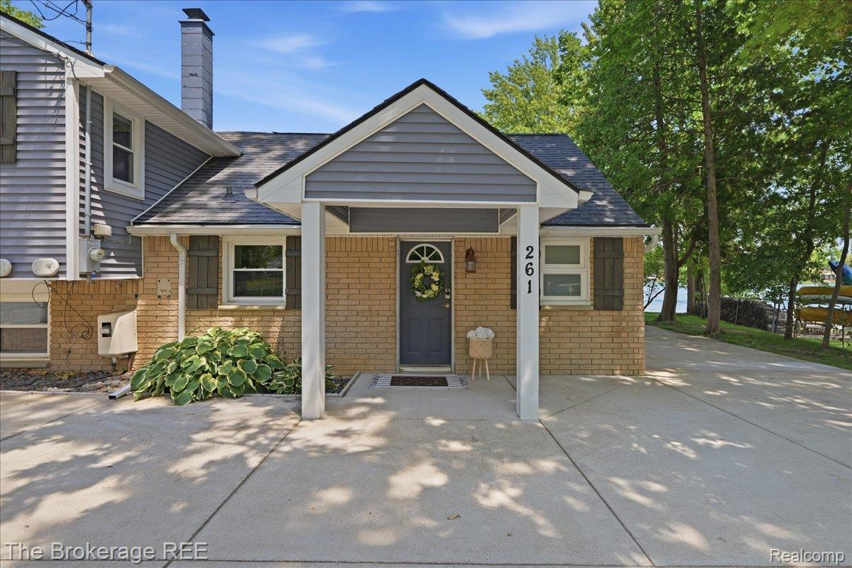 261 Reymont Road Waterford, MI 48327 - Photo 6 of 49 Brick and siding exterior featuring a covered entry, dark shutters, and a paved driveway