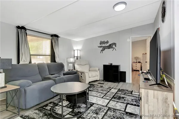 a living room with furniture a flat screen tv and a table