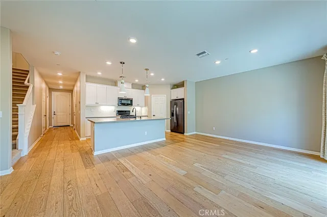 a view of kitchen with kitchen island wooden floor center island and stainless steel appliances
