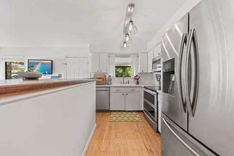 a kitchen with stainless steel appliances a refrigerator sink and white cabinets