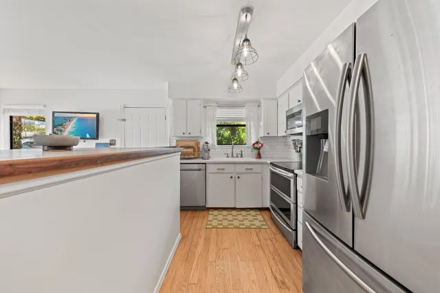 a kitchen with stainless steel appliances a refrigerator sink and white cabinets