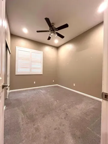 a view of empty room with window and ceiling fan
