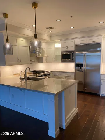 a kitchen with stainless steel appliances granite countertop a sink a stove and a refrigerator