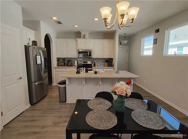 a kitchen with stainless steel appliances granite countertop a dining table chairs and a refrigerator