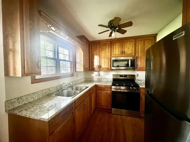 a kitchen with granite countertop stainless steel appliances a sink stove top oven and refrigerator