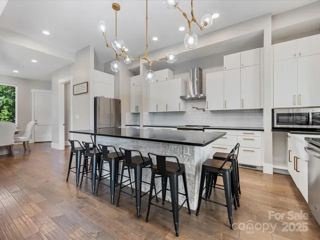an open kitchen with kitchen island granite countertop a dining table chairs sink and cabinets