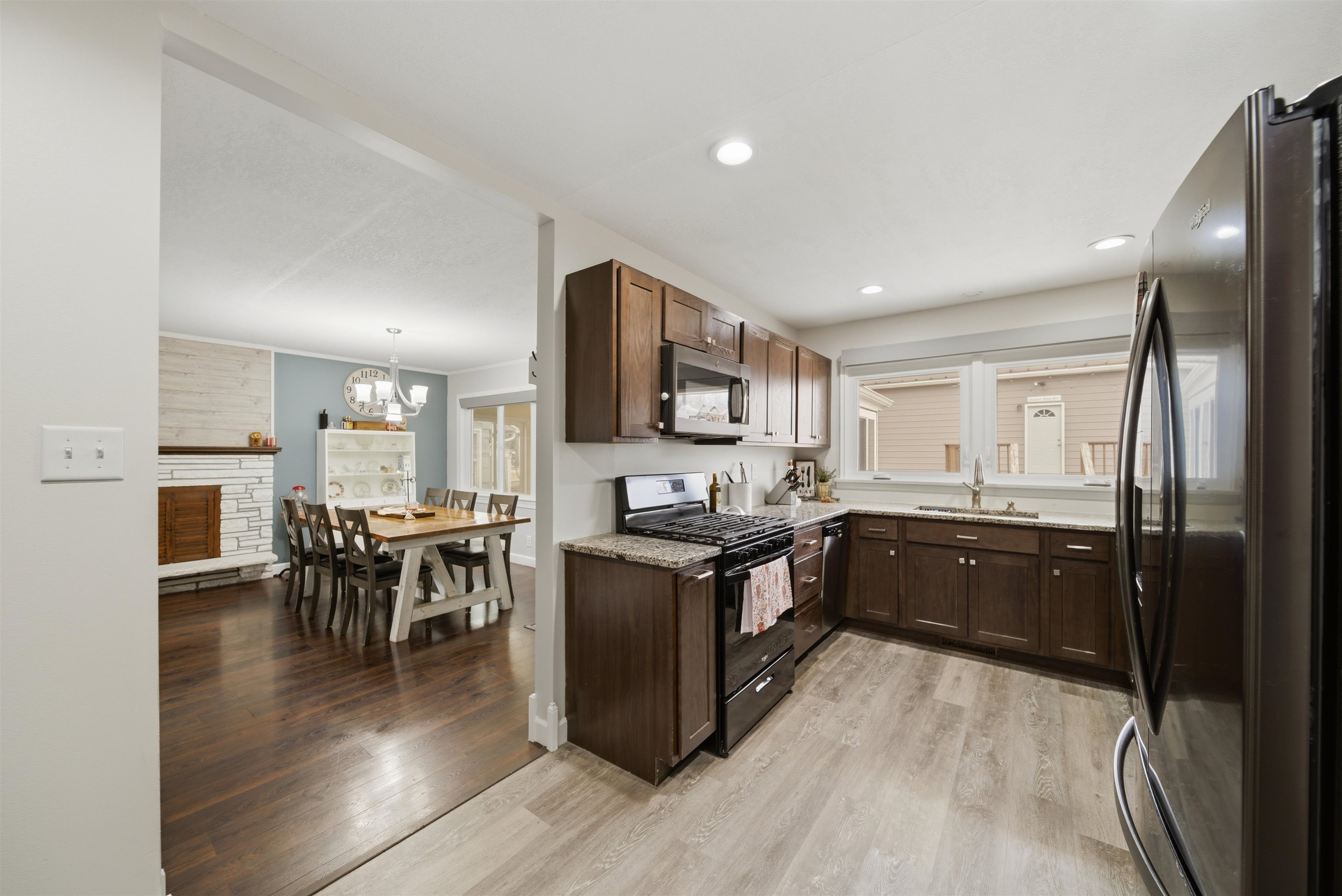 923 Institute Boulevard Dixon, IL 61021 - Photo 16 of 37 a open kitchen with stainless steel appliances granite countertop a stove top oven a sink dishwasher a dining table and chairs with wooden floor