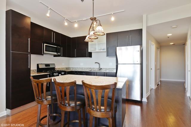 225 South Sangamon Street, Unit 512 Chicago, IL 60607 - Photo 5 of 11 a kitchen with stainless steel appliances granite countertop a refrigerator a stove a sink a microwave oven with a dining table and chairs