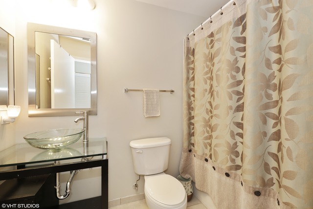 225 South Sangamon Street, Unit 512 Chicago, IL 60607 - Photo 9 of 11 a bathroom with a toilet a sink and a shower curtain