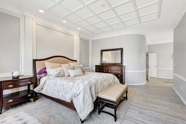 a bedroom with a bed a mirror on dresser and a table chair