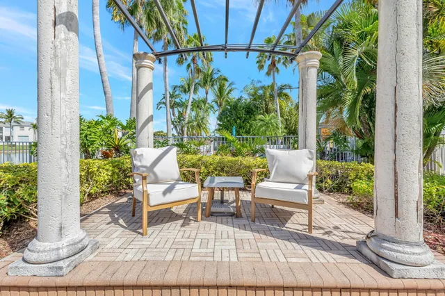 a view of a patio with table and chairs potted plants and floor to ceiling window
