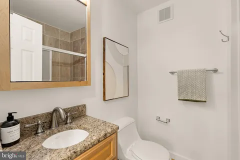 a bathroom with a granite countertop toilet sink and mirror