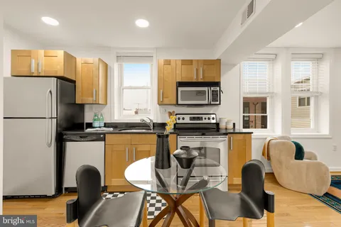 a kitchen with stainless steel appliances granite countertop a refrigerator a stove top oven a sink dishwasher and white cabinets with wooden floor