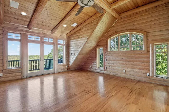 a view of an empty room with wooden floor and a fireplace
