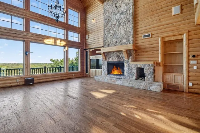 a view of an empty room with wooden floor and a fireplace