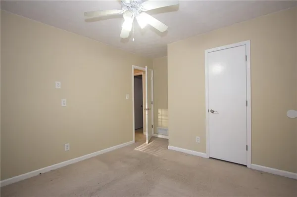 an empty room with a fan & a window
