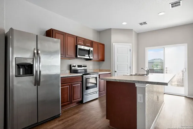 a kitchen with stainless steel appliances granite countertop a refrigerator a stove top oven a sink and dishwasher
