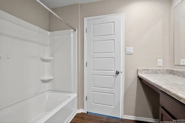 a bathroom with a granite countertop sink and a bathtub