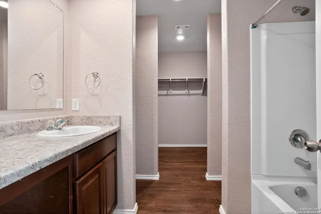 a bathroom with a granite countertop sink a mirror and shower