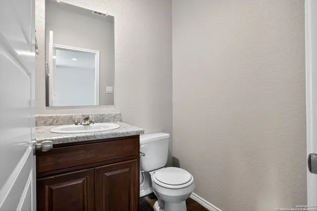 a bathroom with a granite countertop sink toilet and mirror