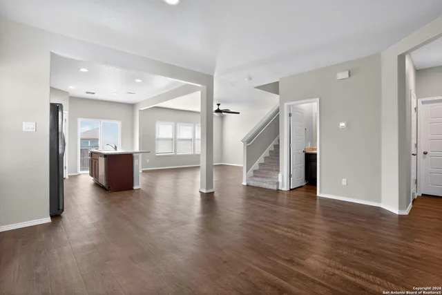 a view of a big room with wooden floor and a kitchen