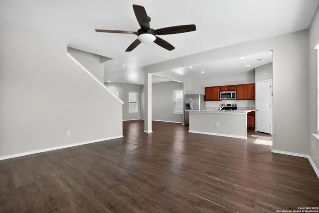 a view of a kitchen with a sink a refrigerator a ceiling fan and wooden floor