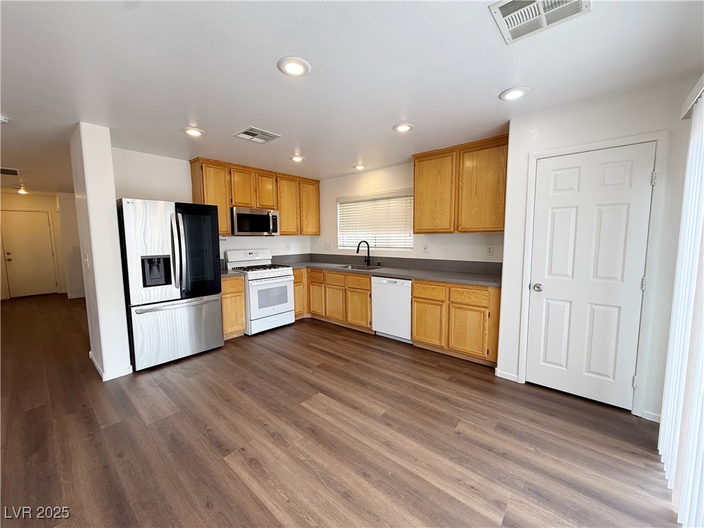 6228 Mercer Valley Street North Las Vegas, NV 89081 - Photo 12 of 41 Kitchen featuring stainless steel appliances, dark wood finished floors, recessed lighting, dark countertops, and light brown cabinets