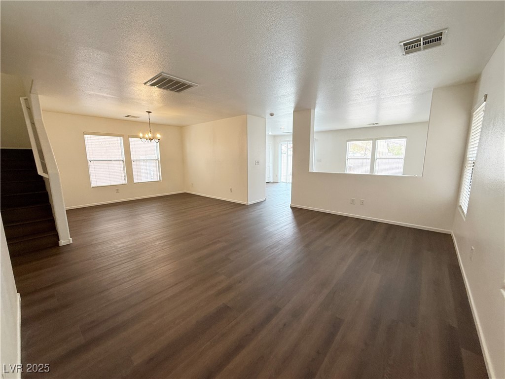 6228 Mercer Valley Street North Las Vegas, NV 89081 - Photo 2 of 41 Unfurnished living room featuring stairs, a chandelier, a textured ceiling, and dark wood-style floors